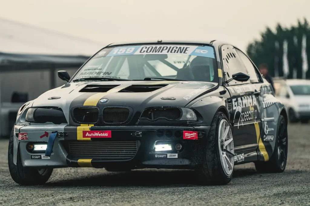 Voiture de course BMW E46 modifiée garée sur gravier, symbole des démarches pour obtenir une licence de pilote automobile en France.