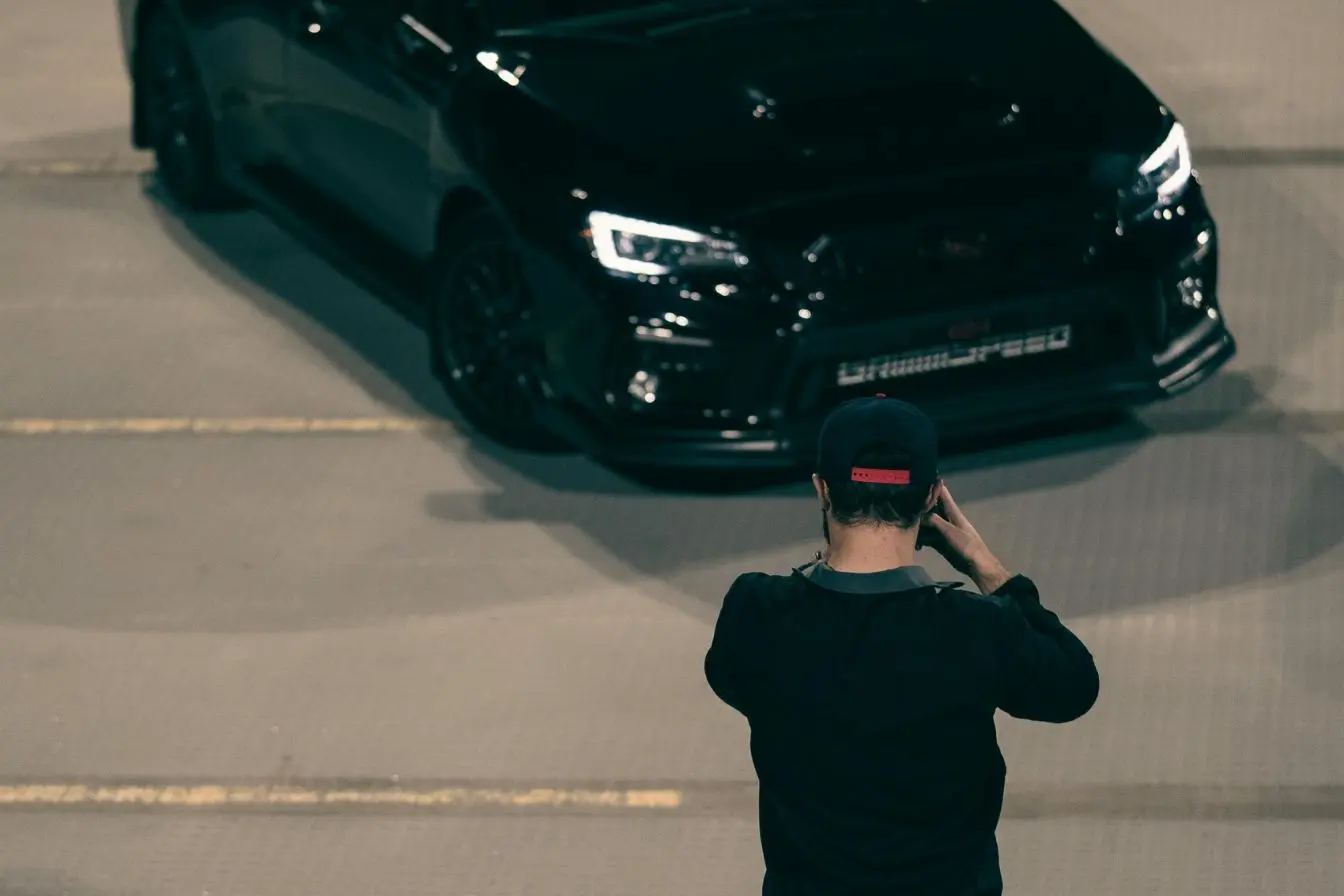 Personne réalisant une séance photo devant une voiture de sport aux lignes élégantes, représentant les premiers pas pour devenir photographe automobile