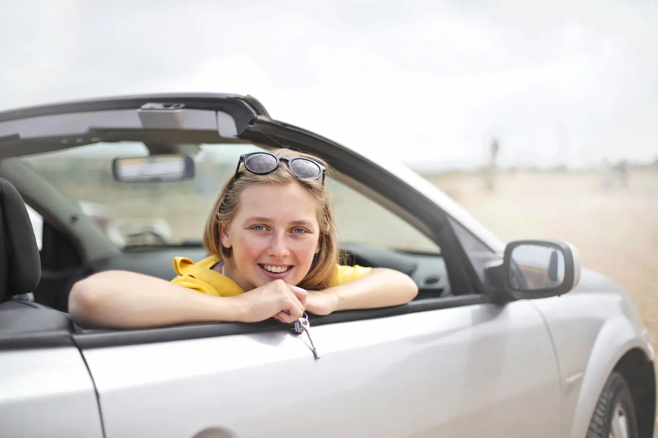 voiture décapotable Personne en haut jaune tenant clé de voiture depuis cabriolet argenté, symbole de l’assurance auto temporaire pour usage ponctuel.
