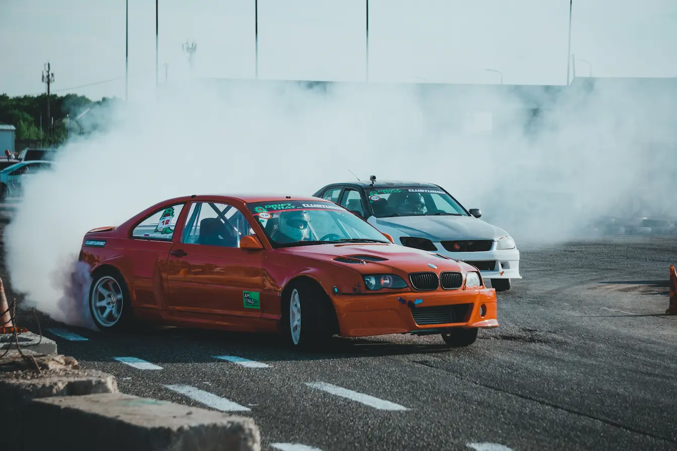 voitures en drift Voiture orange modifiée en drift sur circuit, symbole des besoins spécifiques d’une assurance adaptée aux compétitions automobiles.